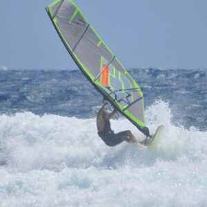 Windsurfer powered up on a wave face with the CHS GS4 wave sail, grey panels and fluo green outline