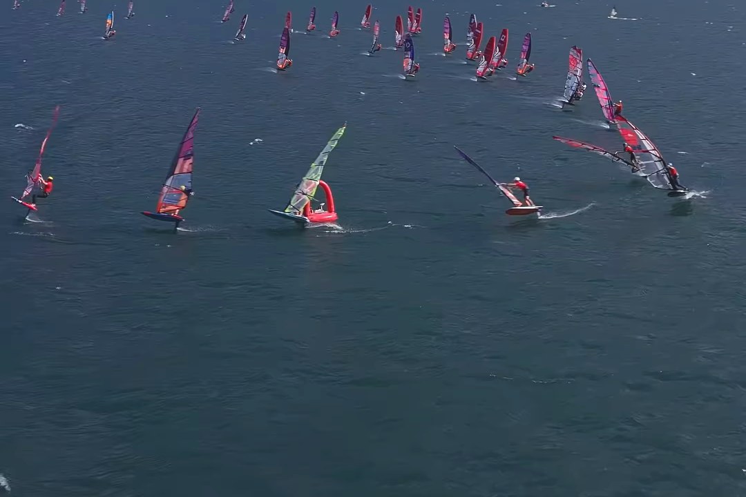 Aerial view of the 45-rider foil slalom fleet rounding a mark at the Austria Slalom Cup 2026 in Torbole, Lake Garda